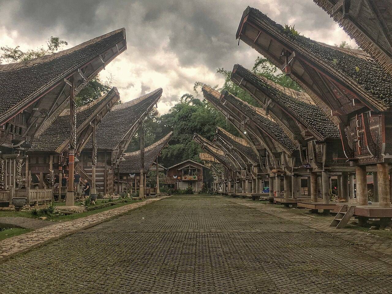 Tongkonan and rice barns facing across a stone-paved compound in Toraja