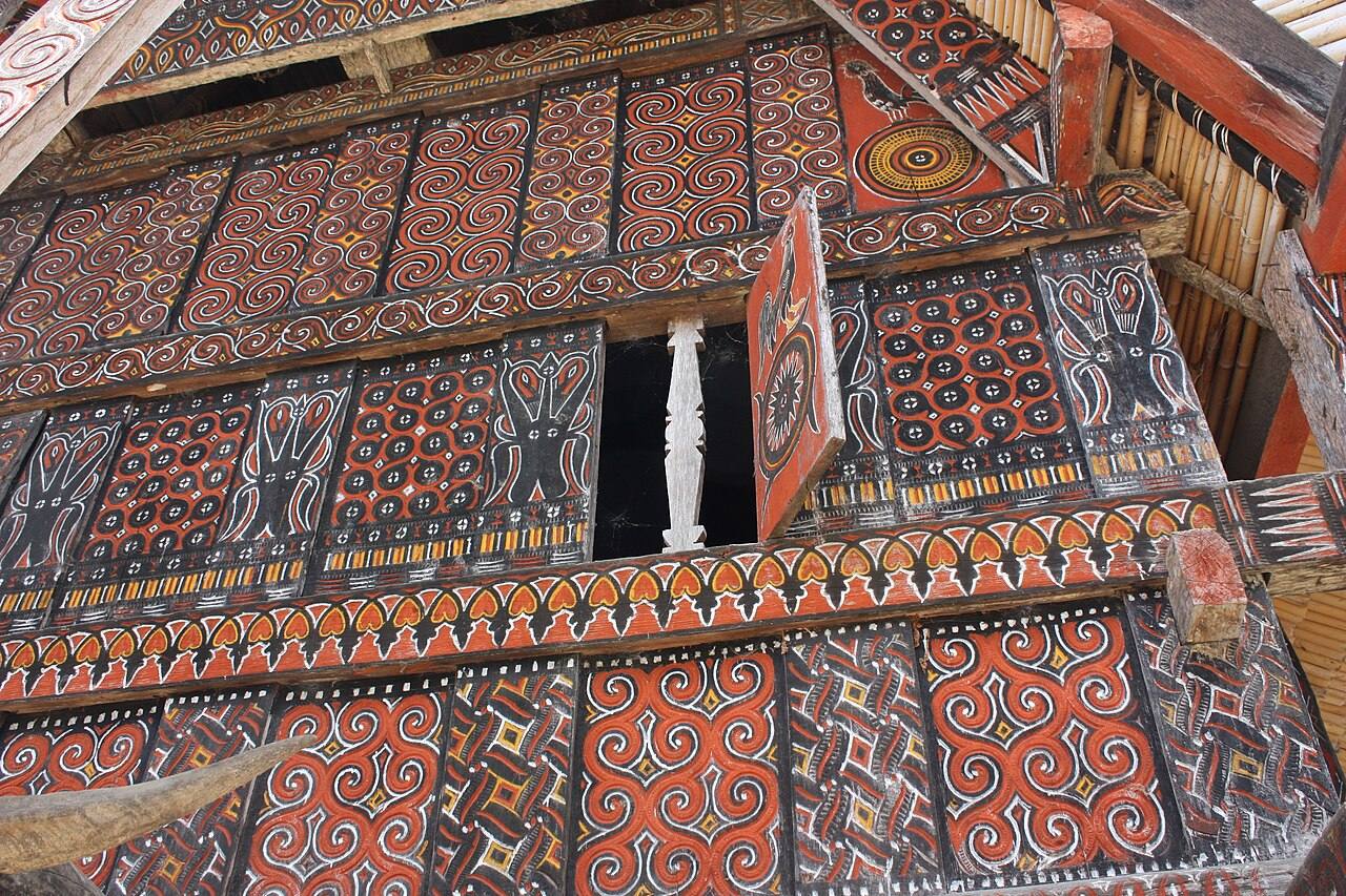 Carved red and black timber panels on a tongkonan at Palawa