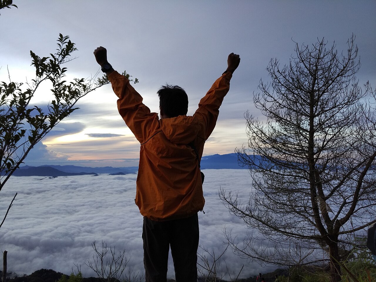 A visitor on Mount Sesean looking over a cloud-filled valley