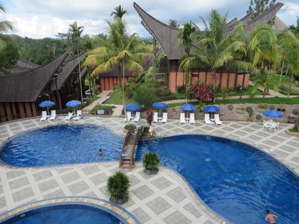Outdoor pool surrounded by palms and tongkonan-style buildings at Toraja Heritage Hotel